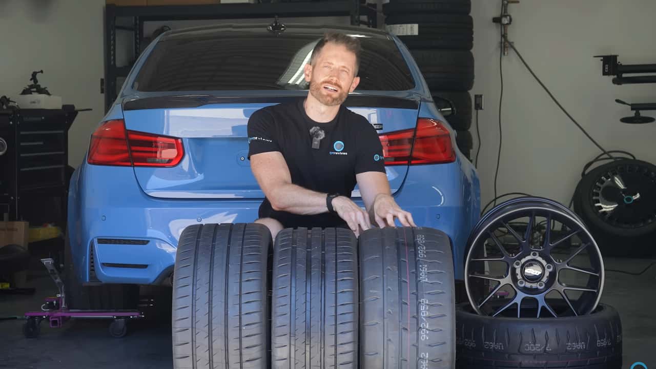man sitting behind a set of tires with a bmw m3 in the background