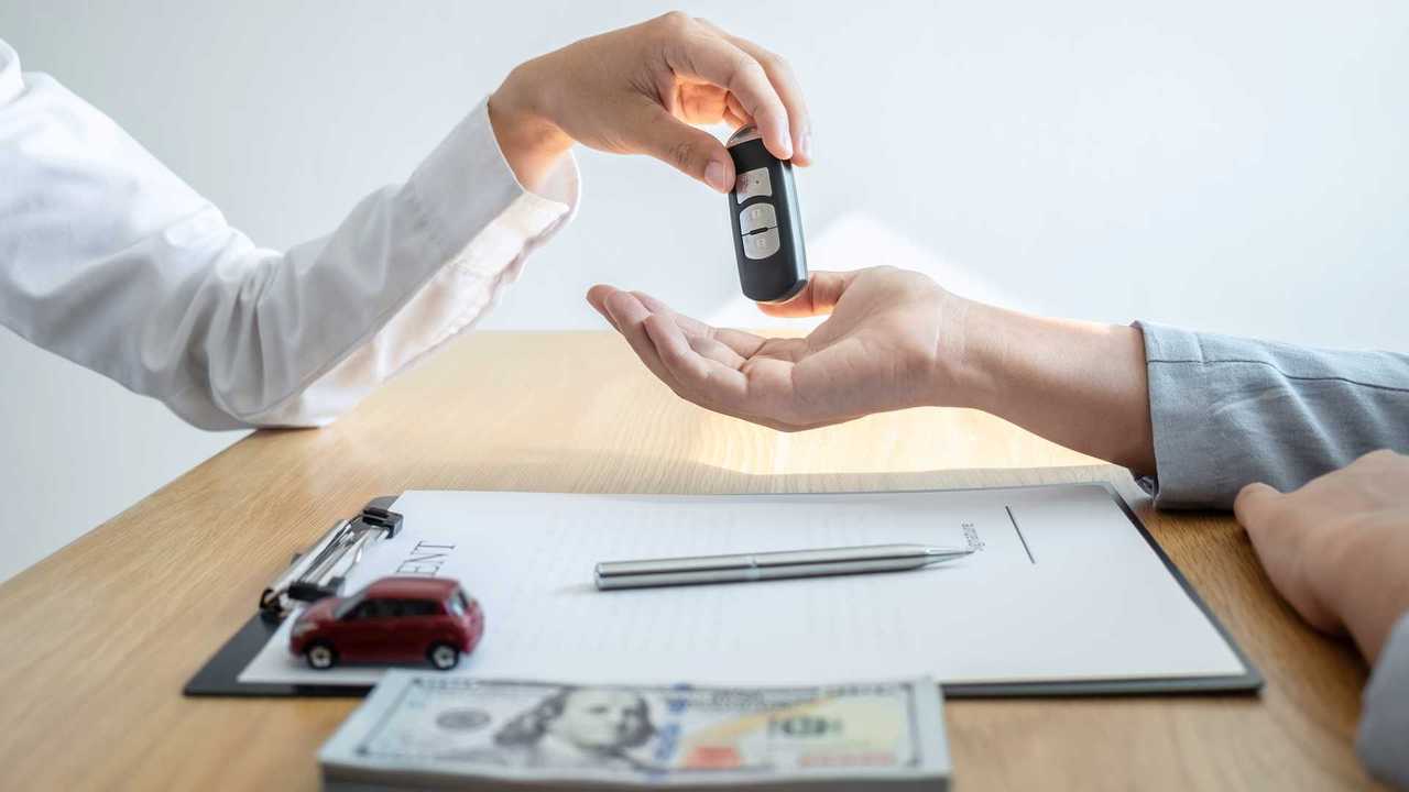 Sales man giving car keys to customer after signing agreement