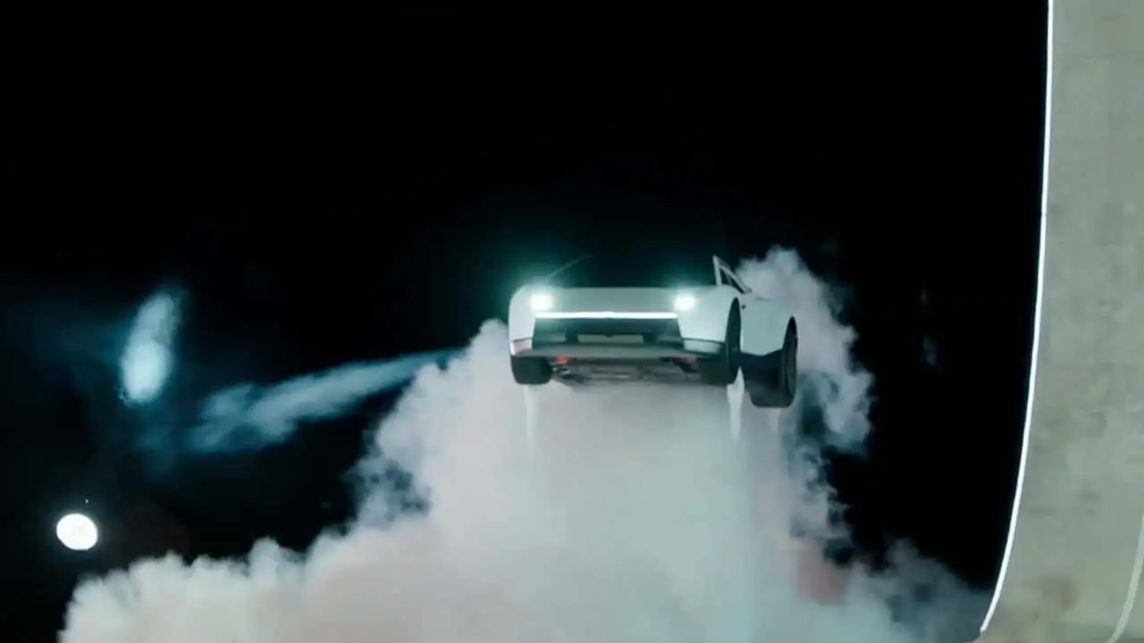 Tesla Roadster airborne beside the curved launch ramp with downward thrusters firing during the demonstration