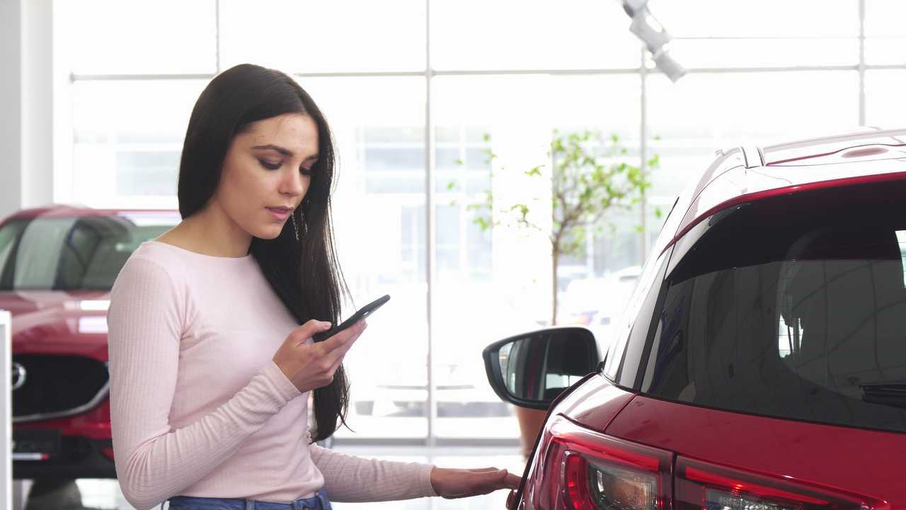 Woman car shopper using smartphone at dealership
