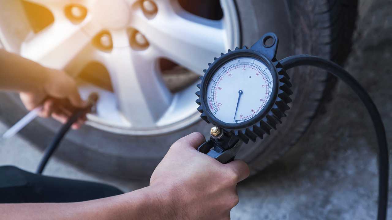 Inflating tyre and checking air pressure with gauge
