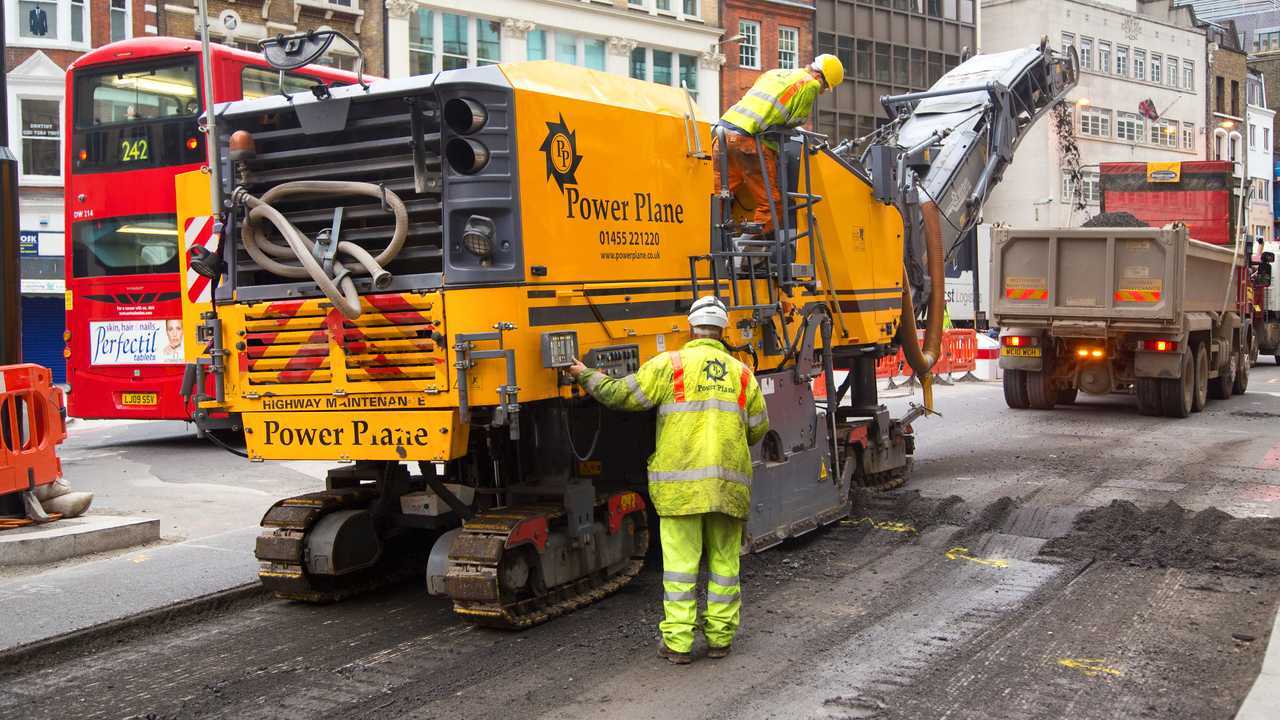 Workman using a cold milling machine in London