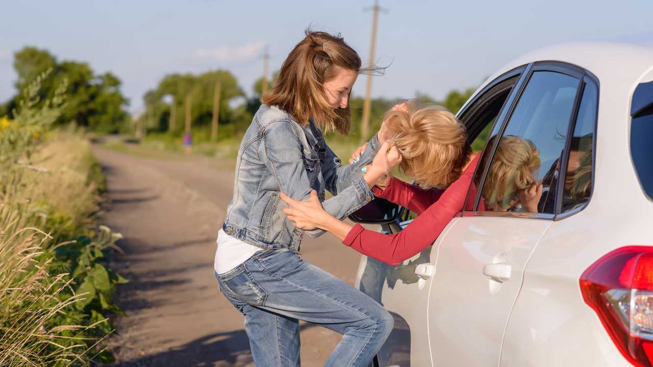 Two women fighting at the roadside on a rural road