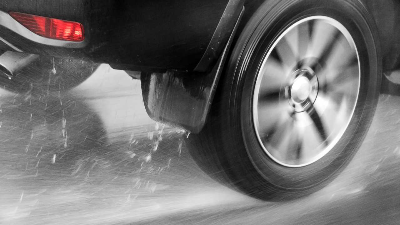 Rear wheel of car driving aquaplaning in rain on wet road