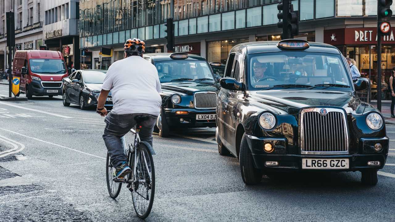 Cyclist going past taxis waiting to turn on Oxford Street in London