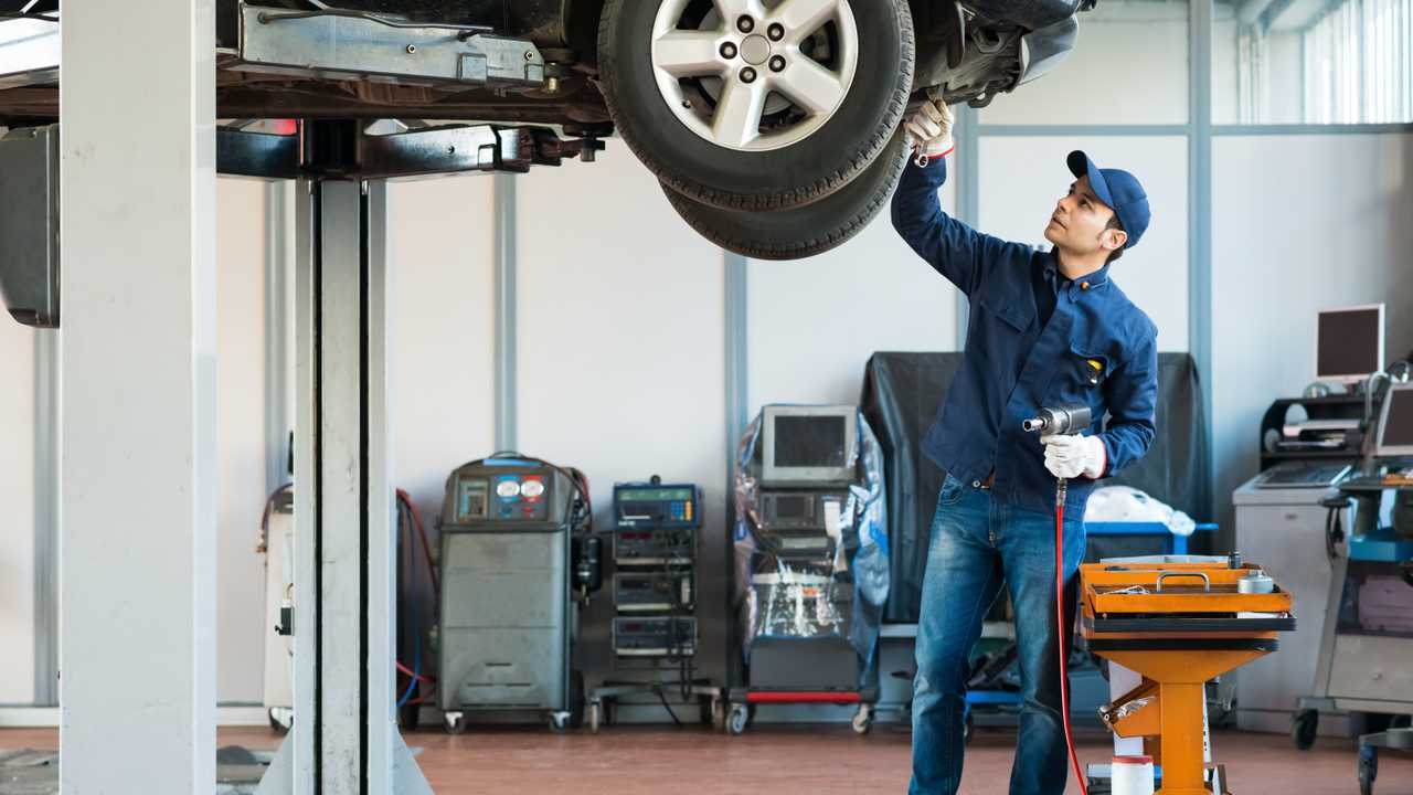 Mechanic working on vehicle on lift