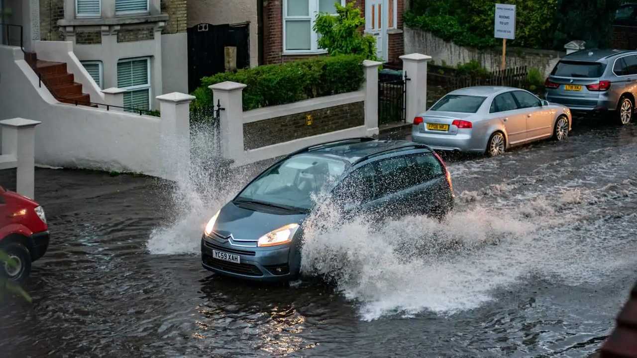 Car driving slowly down flooded street in Gravesend Kent UK