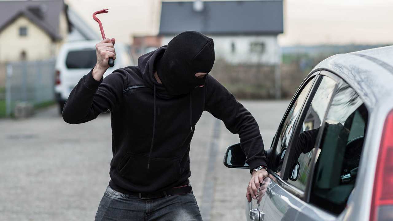 Car thief breaking glass with crowbar