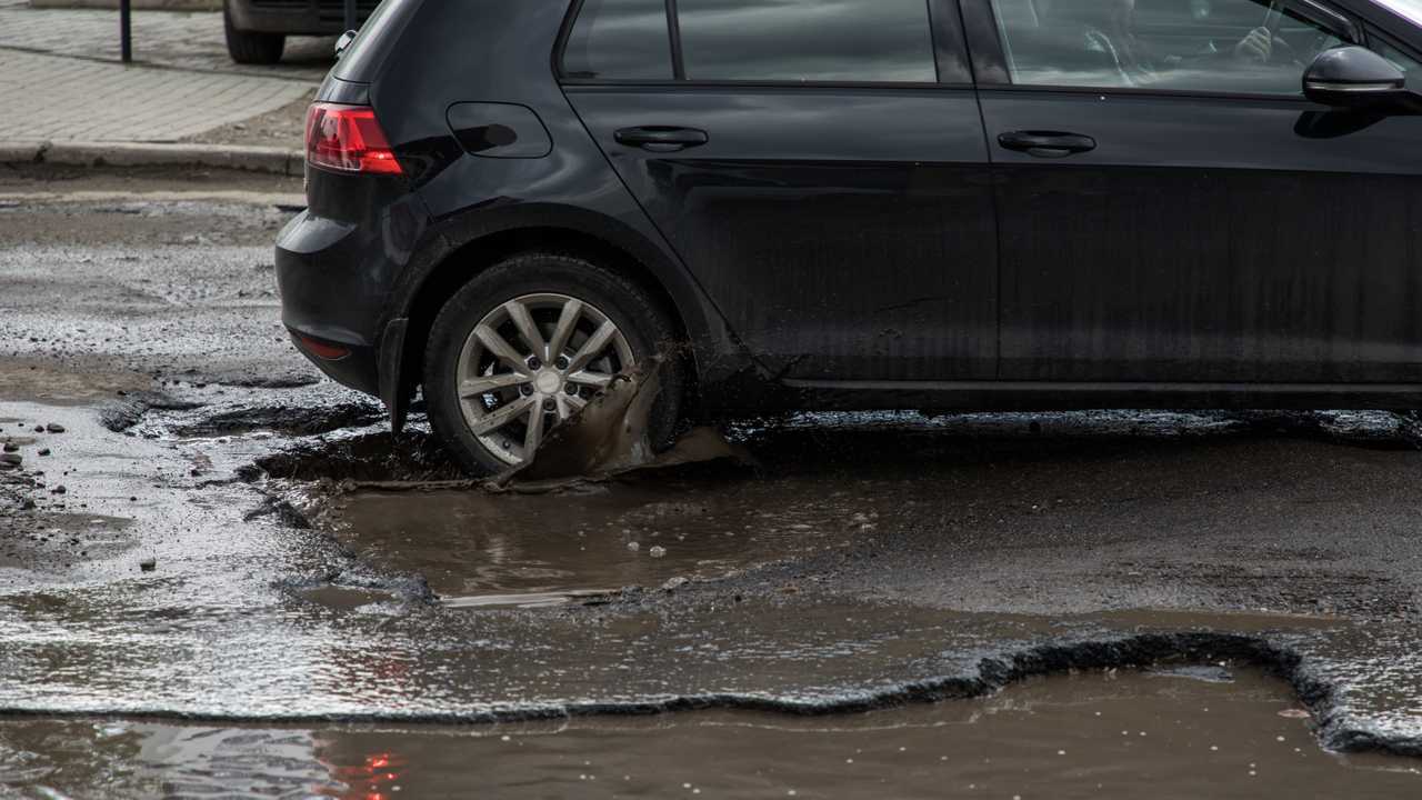 Car hitting pothole in flooded city street