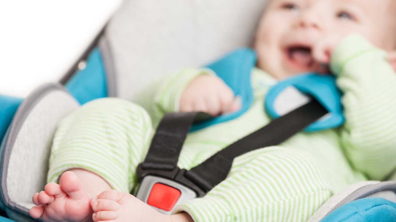 Smiling infant baby in safety car seat