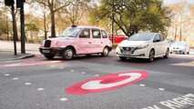 Ultra Low Emissions Zone sign on asphalt with Nissan Leaf and London taxi