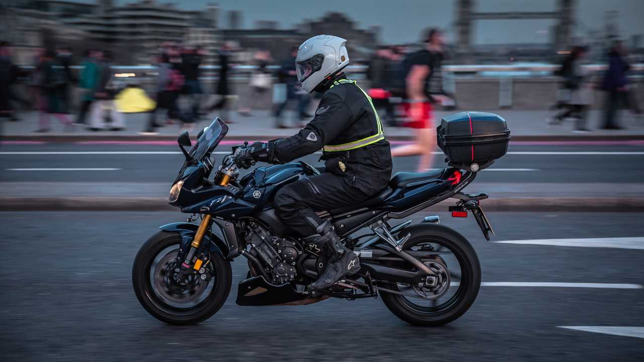 Motorcyclist and commuters crossing London Bridge during rush hour