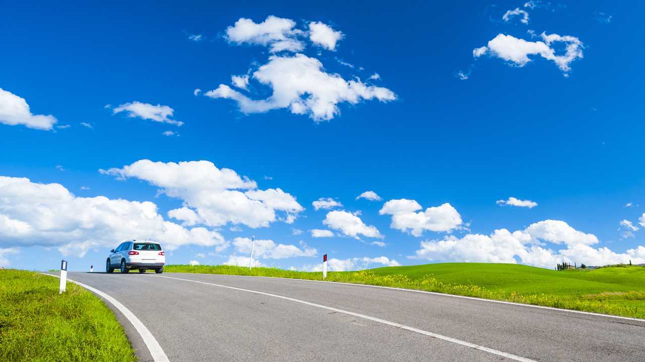 Car driving on open road under big blue skies