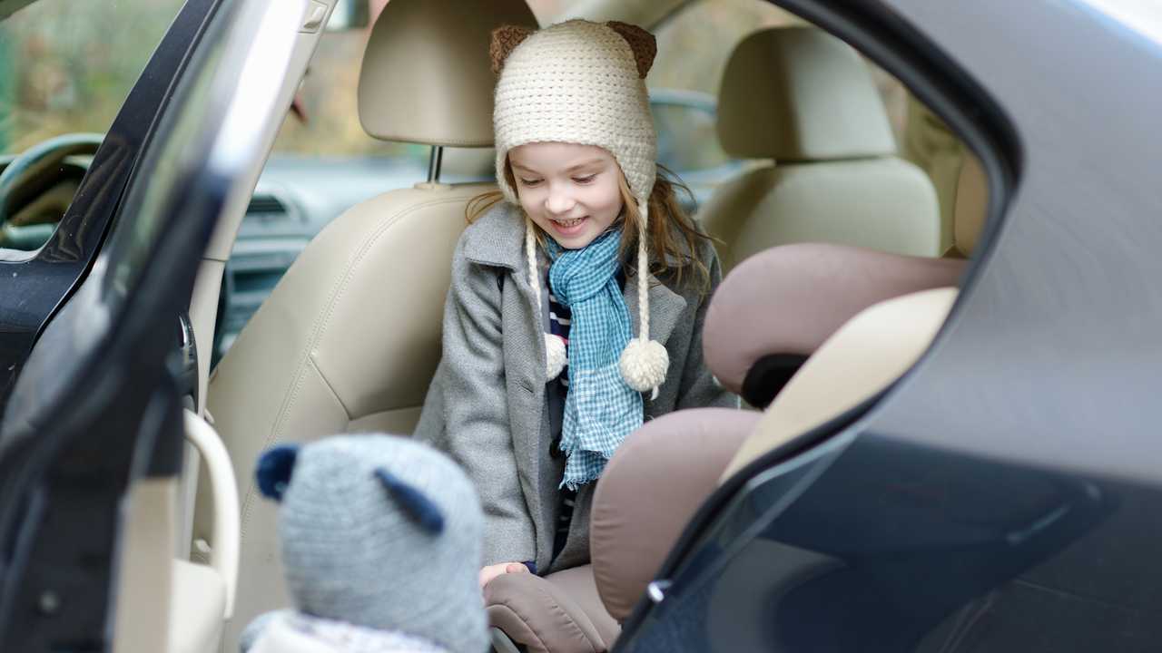 Little girl getting into her car seat