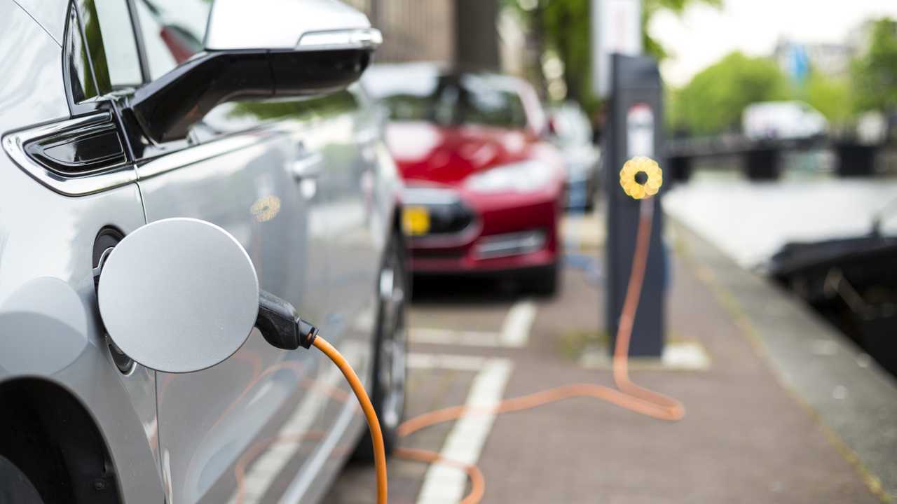 Hybrid car plugged into charging station on street