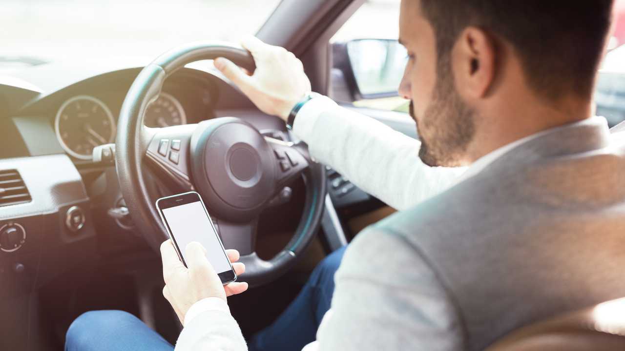 Businessman texting on his mobile phone while driving