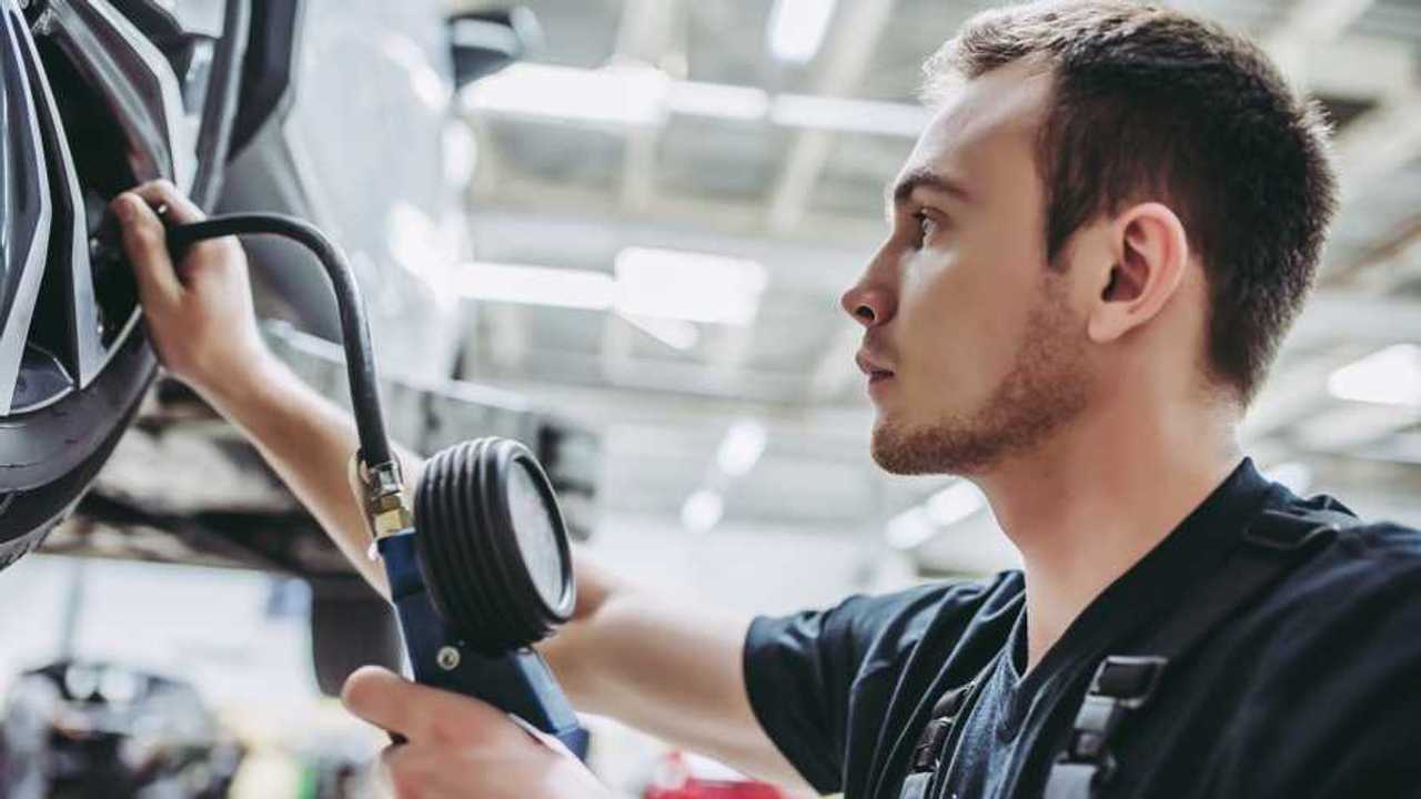 Mechanic in service garage checking tyre pressure