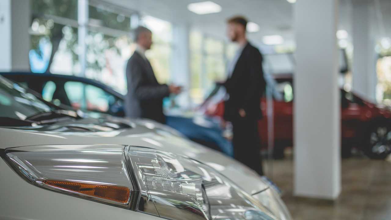 Car salesman talking with buyer in showroom