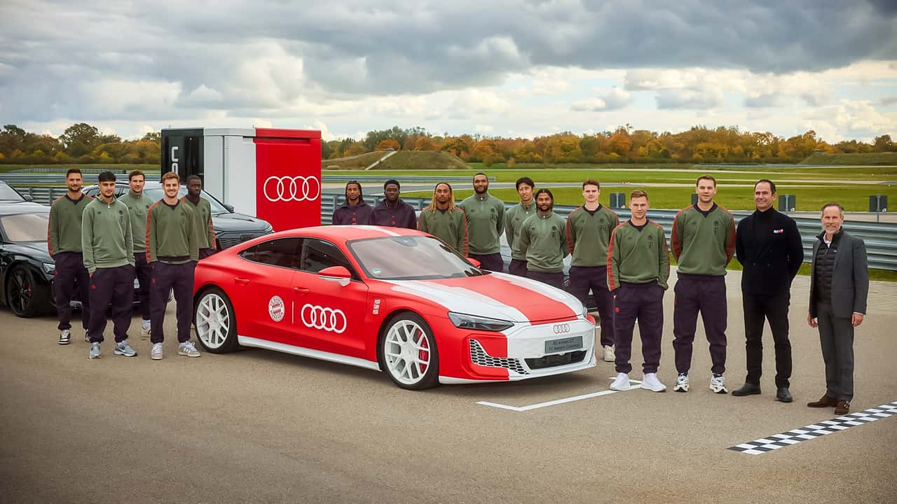 Die Mannschaft des FC Bayern München steht um den speziell folierten Audi RS e-tron GT performance