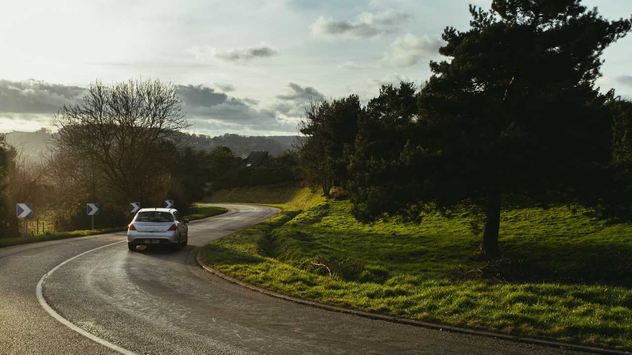 Asphalt road with cars passing through the forest in the region of Normandy France