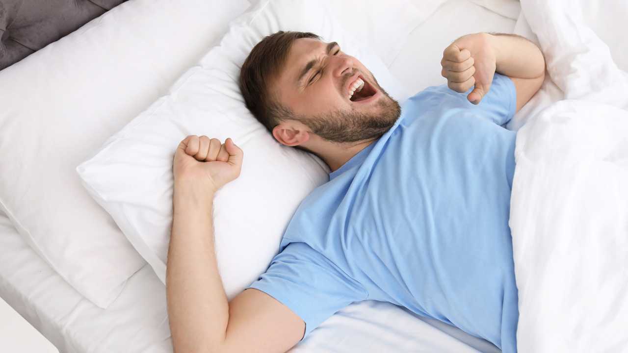 Happy man waking up in bed