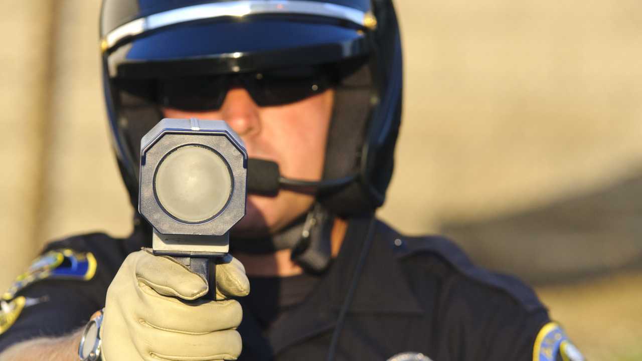 Police officer pointing his radar gun at speeding traffic