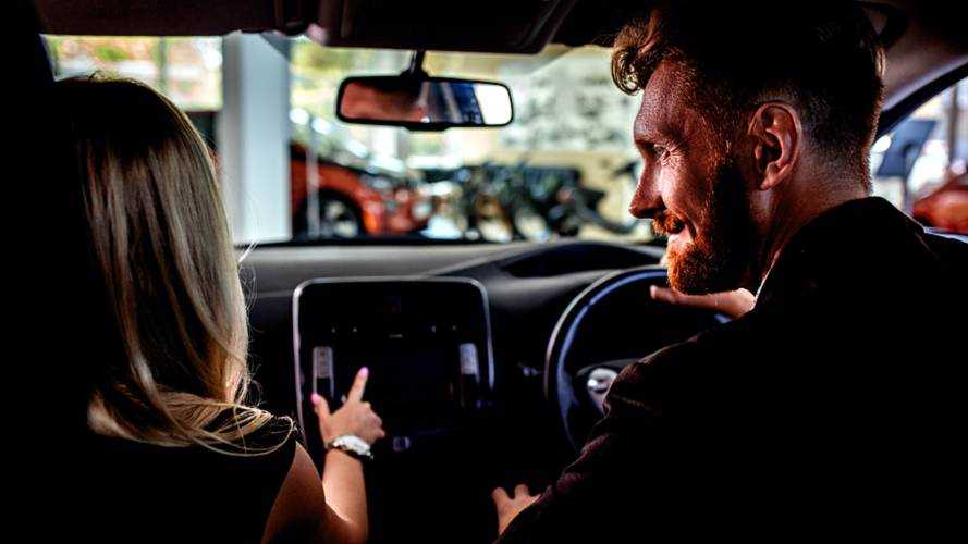 Happy couple in auto showroom choosing new vehicle.