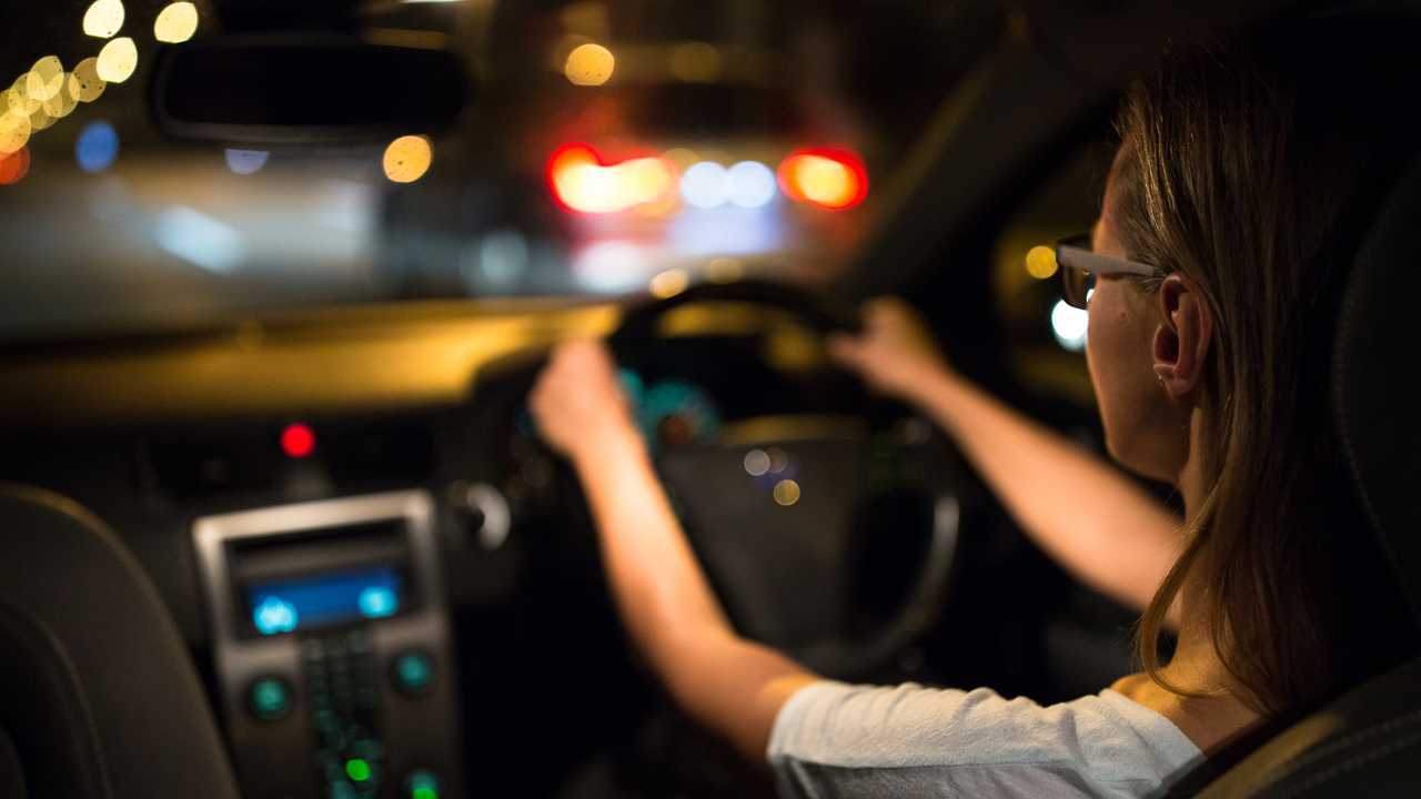 Woman driving car at night in traffic