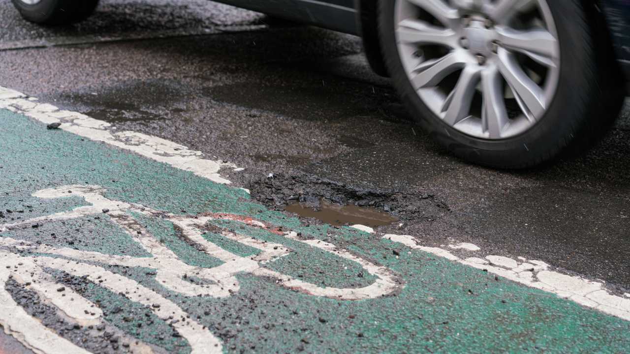 Deep pothole filled with water in Chichester between road and cycle path