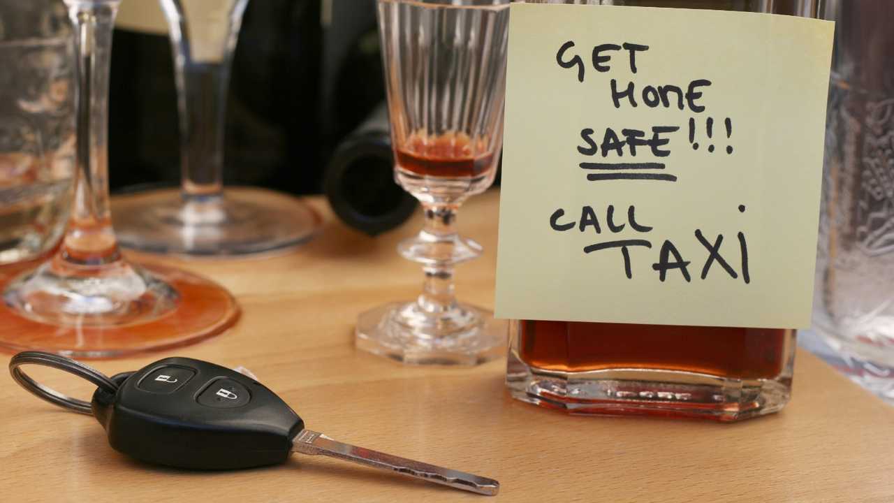 Car keys on table full of empty glasses, bottles at party