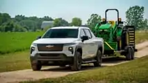 Autocarro da lavoro Chevrolet Silverado EV del 2024 che traina un trattore John Deere