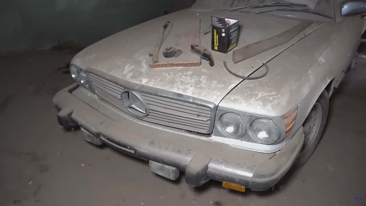 vintage mercedes-benz 450sl front end covered in parts and dust